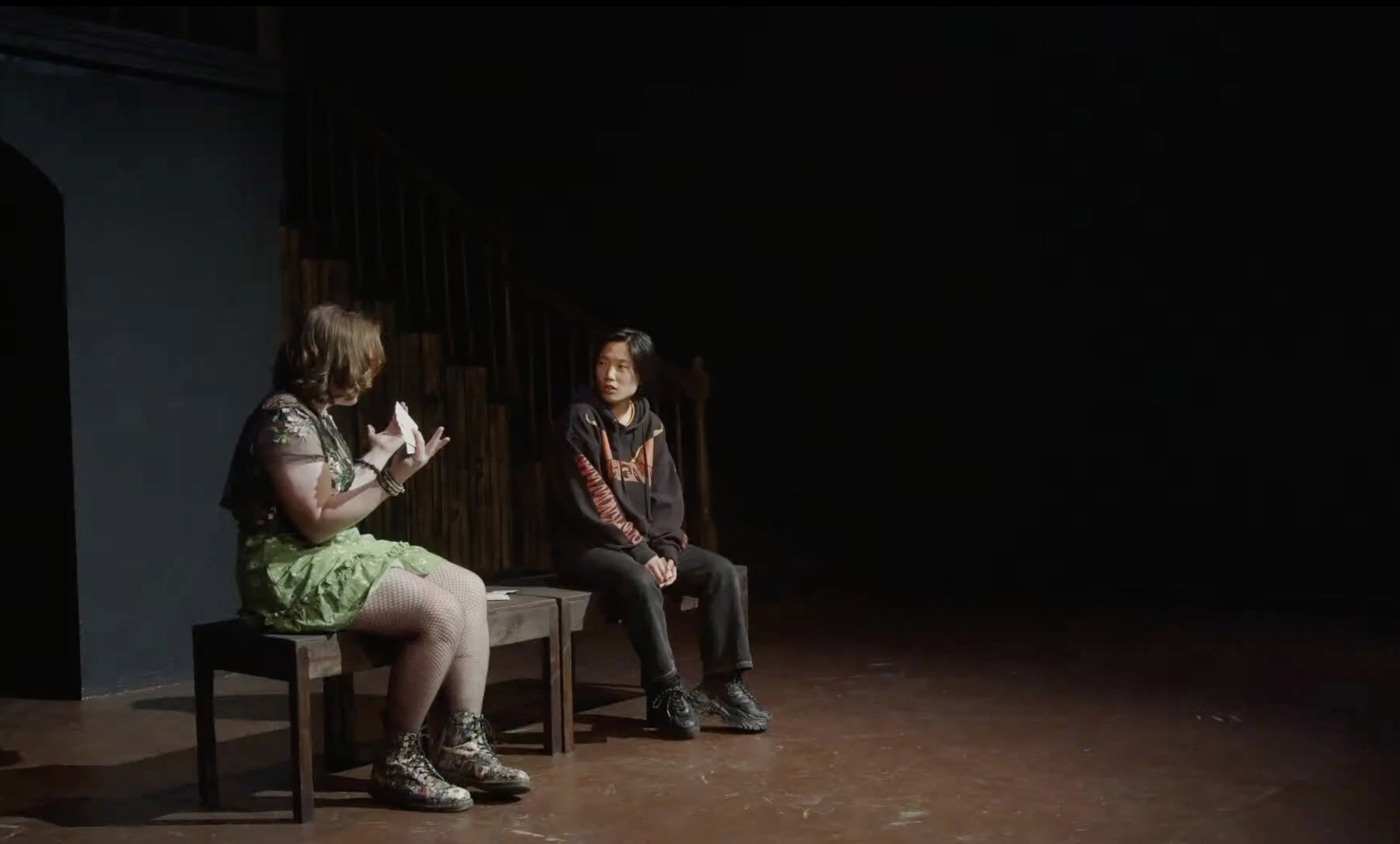 Two actors sitting on a bench during a performance of 'LOCAL PROPHETS: A Play of Near-Collisions.'